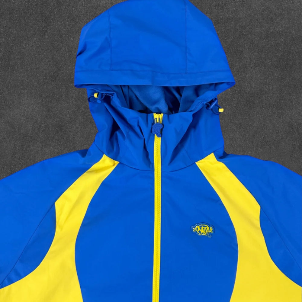 SYNA WORLD VORTEX WOVEN JACKET [BLUE/YELLOW]